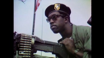 Movie still from “Summer of Soul” (2022), directed by Sanjib Gogoi – A man wearing a hat and holding a gun; Close Up shot, Low angle