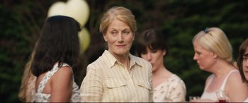 Movie still from “Beast” (2017), directed by Michael Pearce – An older woman standing in front of a group of people; Close Up shot, Over the shoulder angle