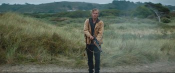 Movie still from “Beast” (2017), directed by Michael Pearce – A man holding a rifle in a field; Medium shot, Low angle