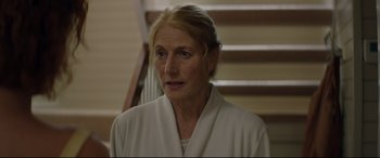 Movie still from “Beast” (2017), directed by Michael Pearce – An older woman wearing a white bathrobe in front of a staircase; Close Up shot, Over the shoulder angle