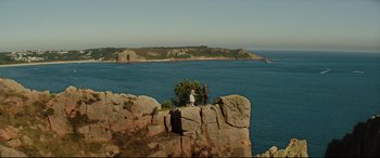 Movie still from “Beast” (2017), directed by Michael Pearce – Two people standing on top of a rock near the ocean; Extreme Wide shot, High angle