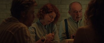 Movie still from “Beast” (2017), directed by Michael Pearce – A woman sitting at a table with a glass of wine in her hand; Medium shot, Over the shoulder angle