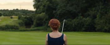 Movie still from “Beast” (2017), directed by Michael Pearce – A woman in a blue dress is holding a golf club; Medium shot, Low angle