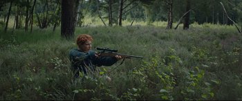 Movie still from “Beast” (2017), directed by Michael Pearce – A man with red hair is holding a rifle in the woods; Wide shot, High angle