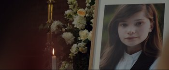 Movie still from “Beast” (2017), directed by Michael Pearce – A picture of a woman in front of some flowers and a candle; Close Up shot, Over the shoulder angle