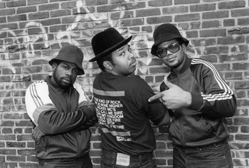 Movie still from “Beastie Boys Story” (2020), directed by Spike Jonze – A group of men standing next to a brick wall; Medium shot, Low angle