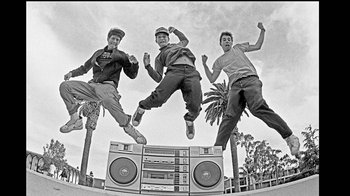 Movie still from “Beastie Boys Story” (2020), directed by Spike Jonze – Three young men jumping in the air next to a boombox; Wide shot, Low angle