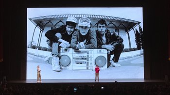 Movie still from “Beastie Boys Story” (2020), directed by Spike Jonze – A man standing in front of a large screen; Wide shot, Low angle