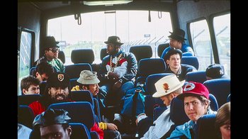 Movie still from “Beastie Boys Story” (2020), directed by Spike Jonze – A group of men sitting on a bus; Wide shot, High angle
