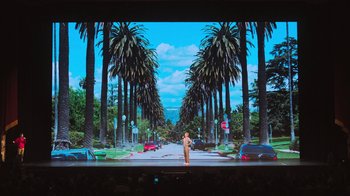 Movie still from “Beastie Boys Story” (2020), directed by Spike Jonze – A man standing in front of palm trees on a stage; Extreme Wide shot, Low angle