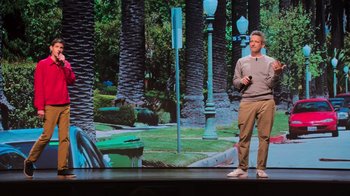 Movie still from “Beastie Boys Story” (2020), directed by Spike Jonze – A man standing on a stage in front of a screen; Wide shot, Low angle