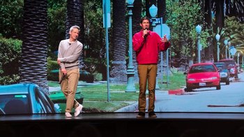 Movie still from “Beastie Boys Story” (2020), directed by Spike Jonze – Two men standing on a stage and one man is holding a microphone; Wide shot, Low angle