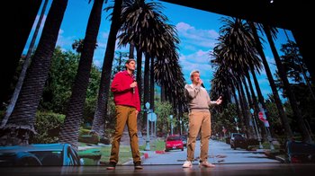 Movie still from “Beastie Boys Story” (2020), directed by Spike Jonze – Two men standing in front of palm trees on a stage; Wide shot, Low angle
