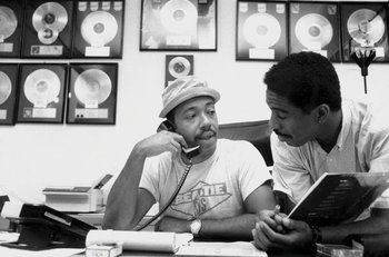 Two men sitting at a table talking on the phone