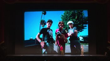 Movie still from “Beastie Boys Story” (2020), directed by Spike Jonze – A group of young men standing next to each other on top of a tv screen; Wide shot, Low angle