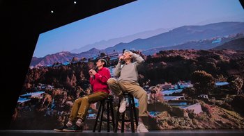 Movie still from “Beastie Boys Story” (2020), directed by Spike Jonze – Two people sitting on stools on a stage; Wide shot, Low angle