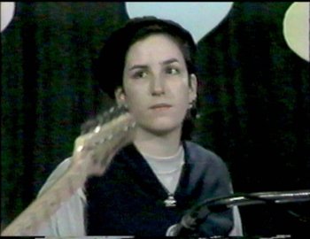 Movie still from “Beastie Boys Story” (2020), directed by Spike Jonze – A woman holding a guitar in front of her face; Close Up shot, High angle
