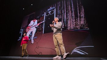Movie still from “Beastie Boys Story” (2020), directed by Spike Jonze – A man standing on a stage singing into a microphone; Wide shot, Low angle