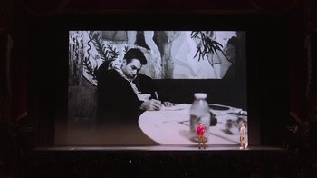Movie still from “Beastie Boys Story” (2020), directed by Spike Jonze – A man is standing in front of a large screen; Wide shot, Low angle