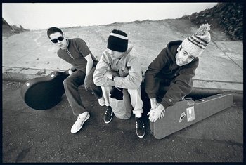 Movie still from “Beastie Boys Story” (2020), directed by Spike Jonze – A group of young men sitting next to each other on the ground; Medium shot, Low angle