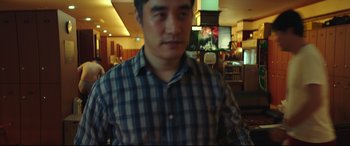 Movie still from “Beasts Clawing at Straws” (2020), directed by Kim Yong-hoon – A man standing in front of a tv in a room; Medium shot, High angle