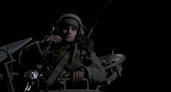 Movie still from “Beaufort” (2007), directed by Joseph Cedar – A man sitting in a chair wearing a helmet and holding a gun; Medium shot, Low angle