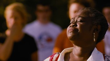 A woman with her eyes closed with other people in the background