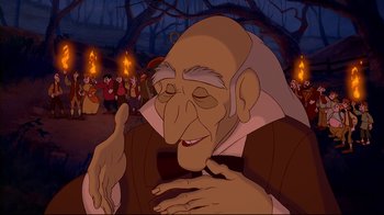 Movie still from “Beauty and the Beast” (1991), directed by Kirk Wise – An old man with a beard is smiling for the camera; Medium shot, Over the shoulder angle