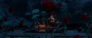 Movie still from “Beauty and the Beast” (2017), directed by Bill Condon – A red rose in front of a large castle at night time; Extreme Wide shot, High angle