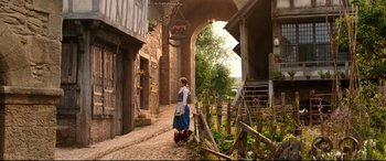 Movie still from “Beauty and the Beast” (2017), directed by Bill Condon – A woman walking down a street with a dog; Wide shot, Low angle