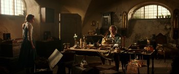 Movie still from “Beauty and the Beast” (2017), directed by Bill Condon – An old man sitting at a table with a lot of stuff on it; Wide shot, High angle