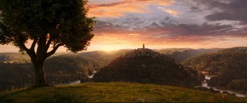 Movie still from “Beauty and the Beast” (2017), directed by Bill Condon – The sun sets over a hill with a castle on top of it; Extreme Wide shot, High angle
