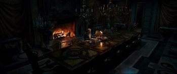 Movie still from “Beauty and the Beast” (2017), directed by Bill Condon – A group of people sitting at a table in front of a fireplace; Wide shot, High angle