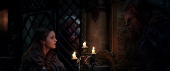 Movie still from “Beauty and the Beast” (2017), directed by Bill Condon – A woman sitting in front of three lit candles; Medium shot, Over the shoulder angle