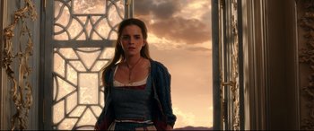 Movie still from “Beauty and the Beast” (2017), directed by Bill Condon – A woman standing in front of a window with clouds in the background; Medium shot, Low angle
