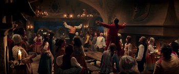 Movie still from “Beauty and the Beast” (2017), directed by Bill Condon – A group of people sitting in a room with candles; Wide shot, High angle