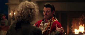 Movie still from “Beauty and the Beast” (2017), directed by Bill Condon – A man in a red jacket is talking to another man; Close Up shot, Over the shoulder angle