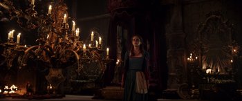 Movie still from “Beauty and the Beast” (2017), directed by Bill Condon – A woman standing in front of a group of candles in a room; Wide shot, Low angle
