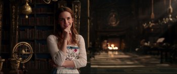 Movie still from “Beauty and the Beast” (2017), directed by Bill Condon – A beautiful young lady standing in front of a fireplace; Medium shot, Over the shoulder angle