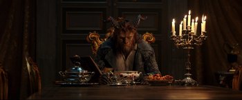 Movie still from “Beauty and the Beast” (2017), directed by Bill Condon – A man sitting at a table with a bowl of food; Medium shot, High angle