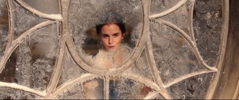 Movie still from “Beauty and the Beast” (2017), directed by Bill Condon – A woman is looking through a window in a castle; Close Up shot, Over the shoulder angle