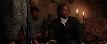 Movie still from “Beauty and the Beast” (2017), directed by Bill Condon – A man sitting in front of another man holding a cup; Medium shot, Over the shoulder angle