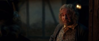 Movie still from “Beauty and the Beast” (2017), directed by Bill Condon – An older man with a beard and a tie; Medium shot, Over the shoulder angle
