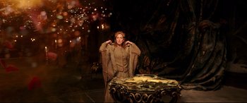 Movie still from “Beauty and the Beast” (2017), directed by Bill Condon – A woman standing next to a table in a room; Wide shot, High angle