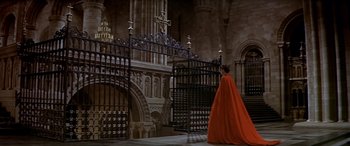 Movie still from “Becket” (1964), directed by Peter Glenville – A woman in a red cape walking through a gate; Extreme Wide shot, High angle