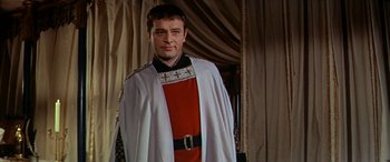 Movie still from “Becket” (1964), directed by Peter Glenville – A man in a red and white outfit standing in front of a curtain; Medium shot, Low angle