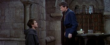 Movie still from “Becket” (1964), directed by Peter Glenville – A man in a blue shirt is talking to a boy in a black robe; Medium shot, Over the shoulder angle