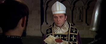 Movie still from “Becket” (1964), directed by Peter Glenville – A man in a priest's outfit holding a wax seal; Medium shot, High angle
