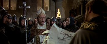 Movie still from “Becket” (1964), directed by Peter Glenville – A man in a priest's outfit is reading a newspaper; Medium shot, High angle