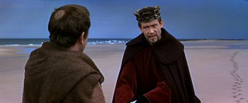 Movie still from “Becket” (1964), directed by Peter Glenville – A man wearing a crown talking to another man on the beach; Medium shot, Over the shoulder angle